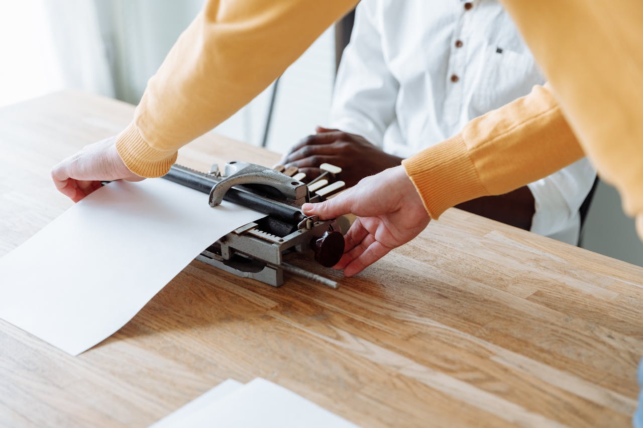 A close-up of hands using a braille typewriter on a wooden table, emphasizing accessibility.